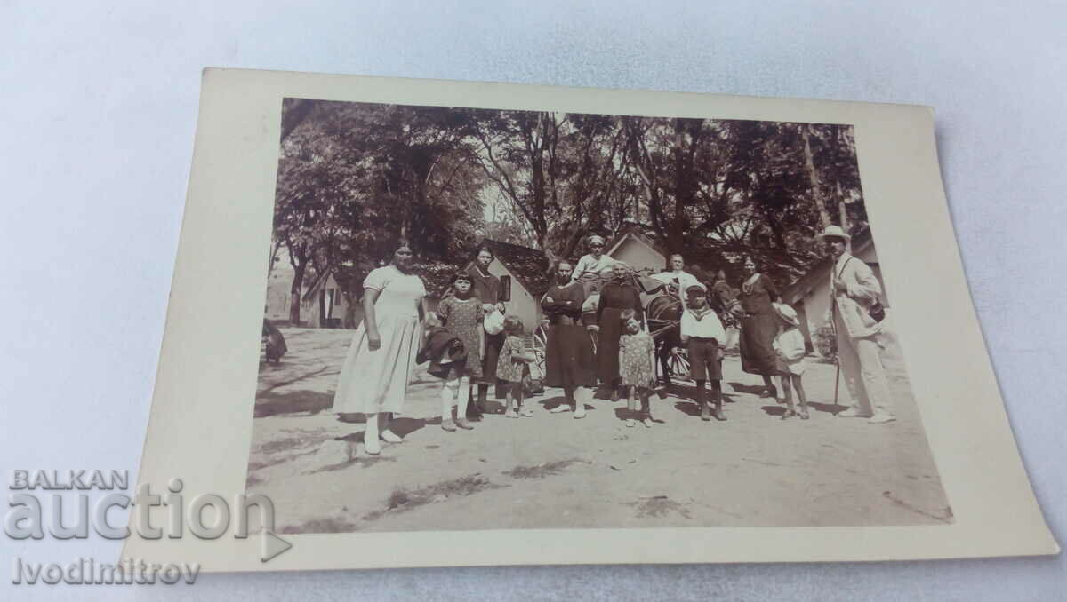 Photo Two men women and children in front of a bungalow