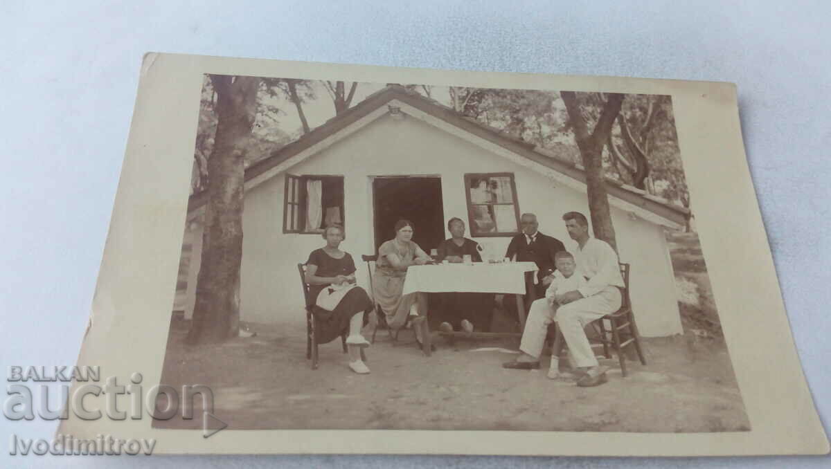 Photo Two men women and a boy in front of a massive bungalow