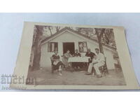 Photo Two men women and a boy in front of a massive bungalow