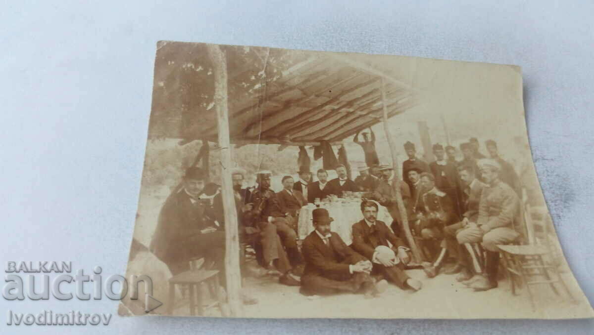 Photo Officer and men having a drink under a shed