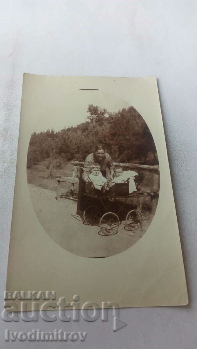 Φωτογραφία Γυναίκα και δύο μωρά σε ένα ρετρό καροτσάκι