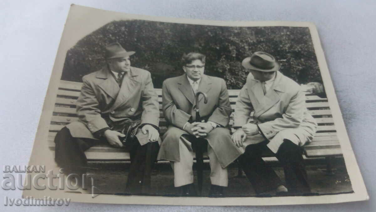 Φωτογραφία Τρεις άνδρες που κάθονται σε ένα παγκάκι στο πάρκο