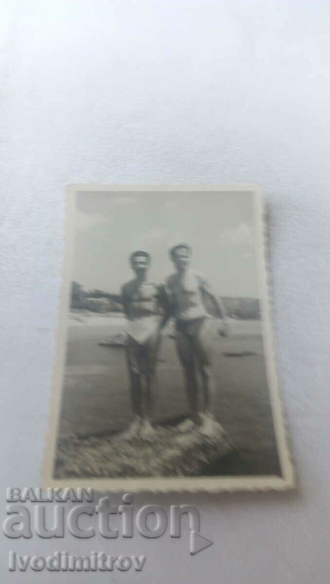 Photo Two men in swimsuits on a cliff above the sea