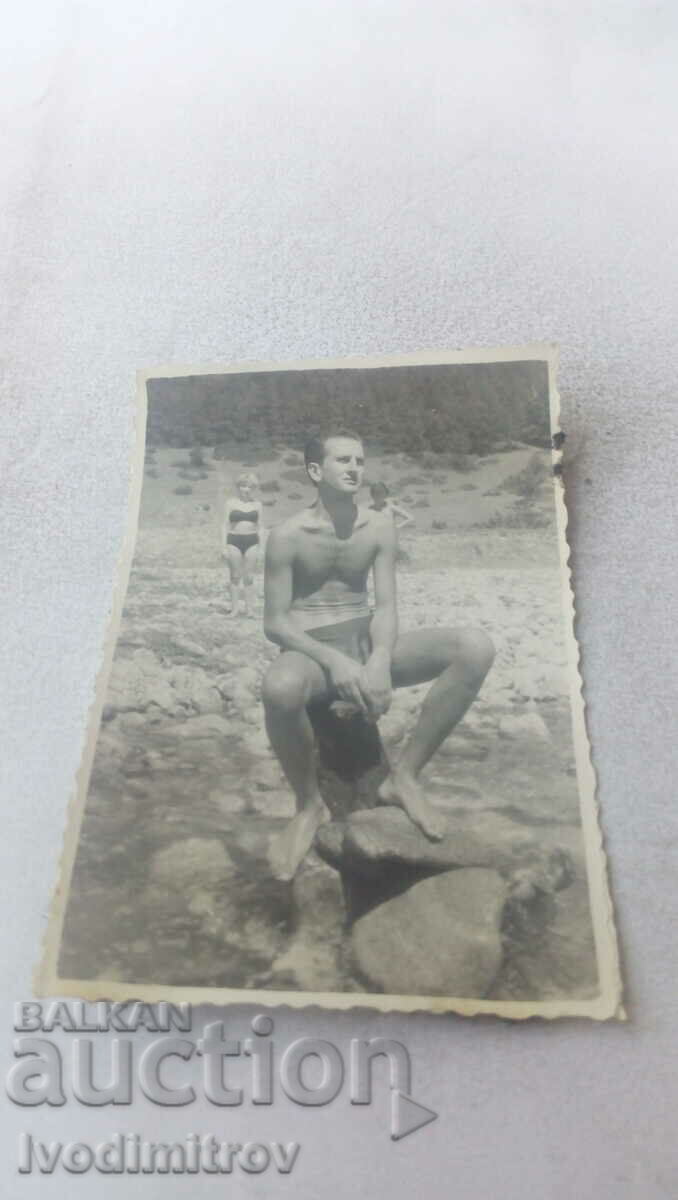 Photo A man with shorts on a stone in the river