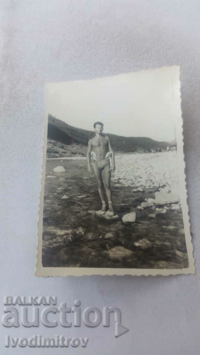 Fotografie Un bărbat în costum de baie pe o piatră din râu