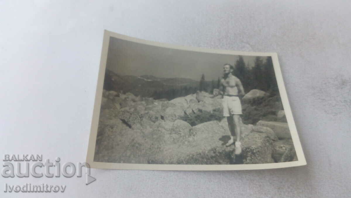Photo Man in shorts on rocks in the forest