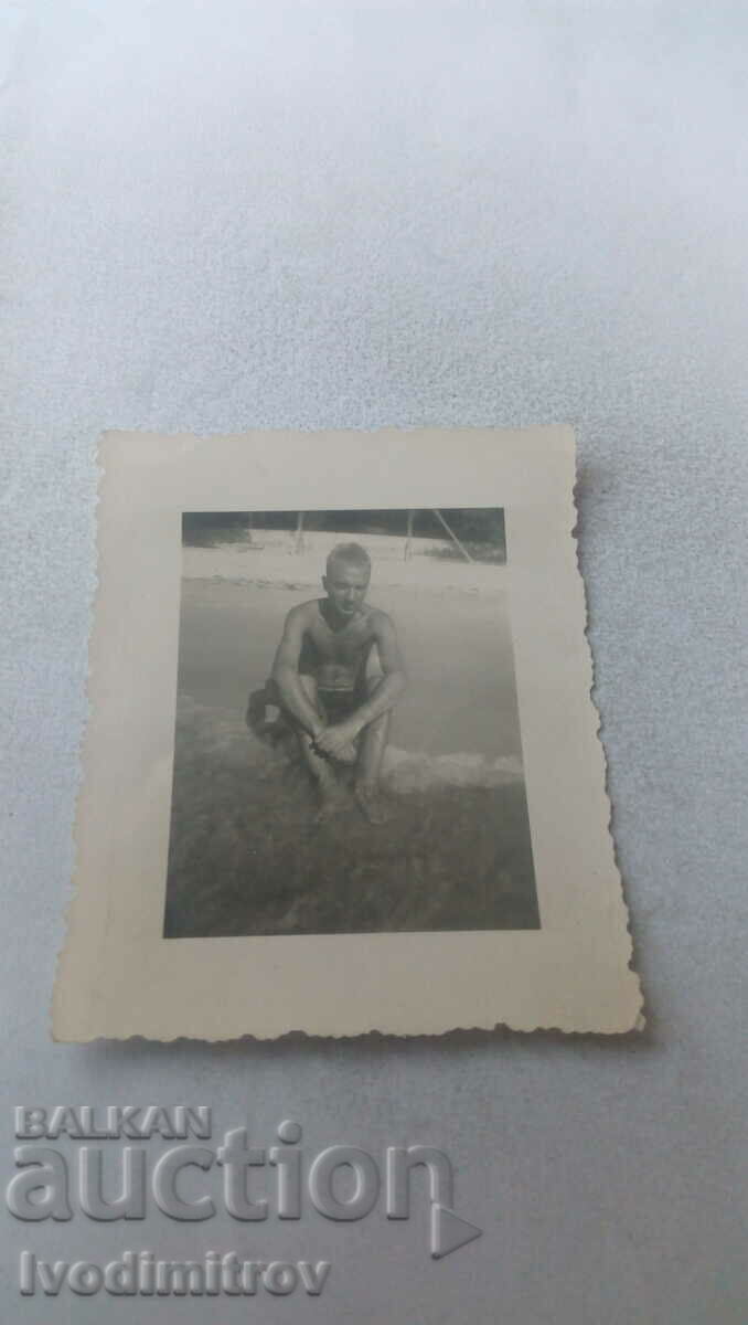 Photo A man in shorts sitting on the grass