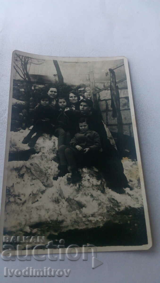 Photo Two young women and three children on a pile of snow