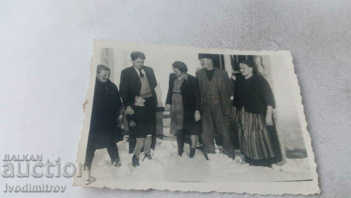 Photo Men, women and a boy in the snow in front of their house