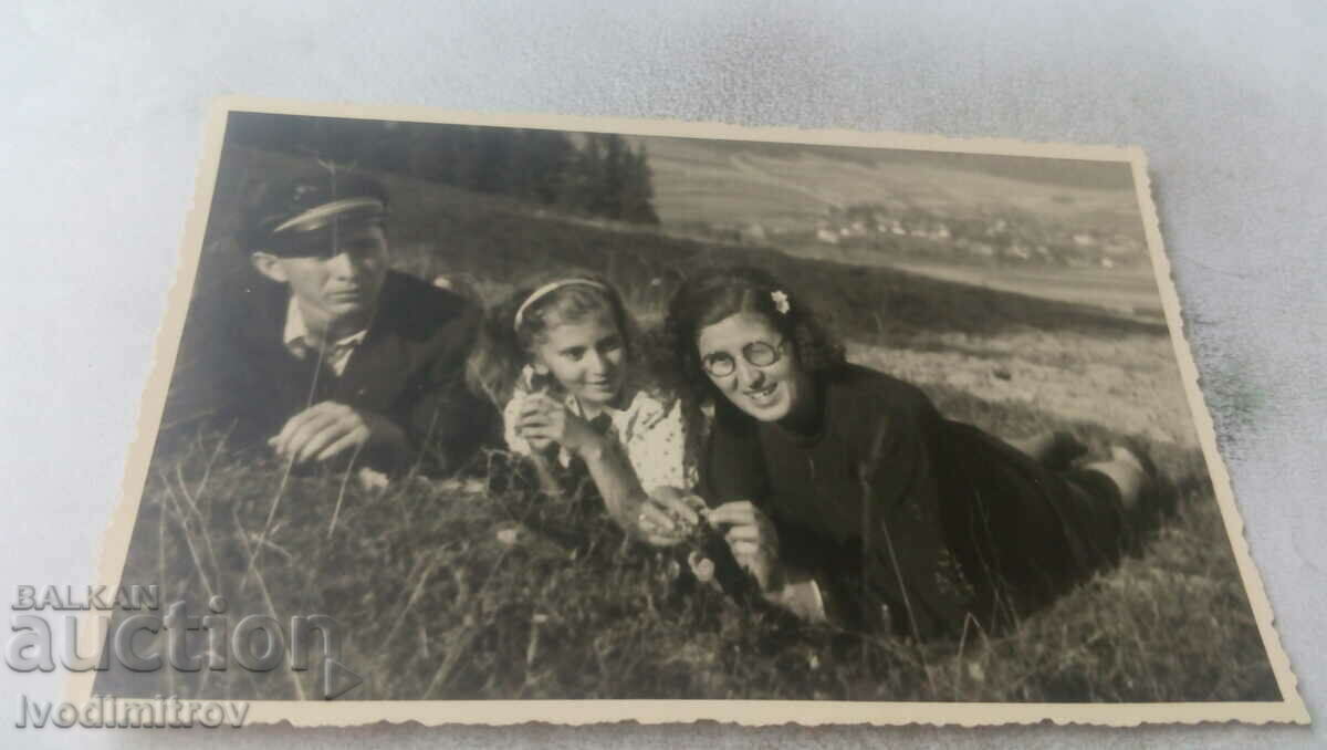 Φωτογραφία Άνδρας γυναίκα και κορίτσι που βρίσκονται στο γρασίδι