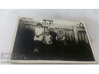 Photo A man and three children in front of a wooden fence