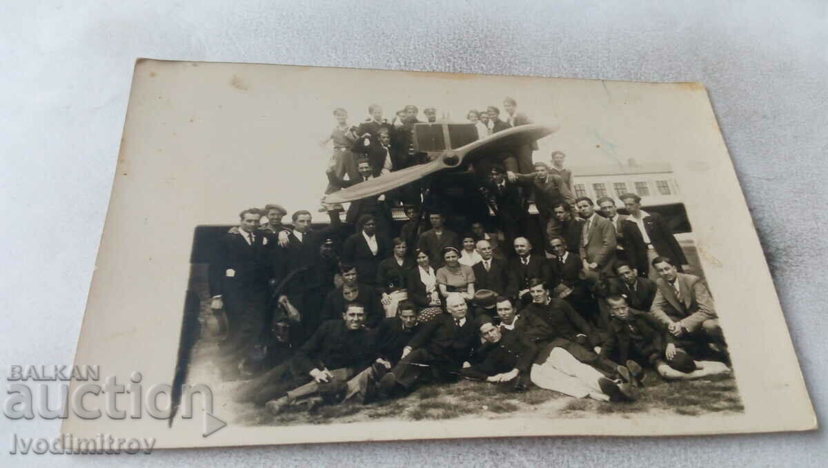 Foto Bărbați, femei și tineri în fața unui avion cu elice