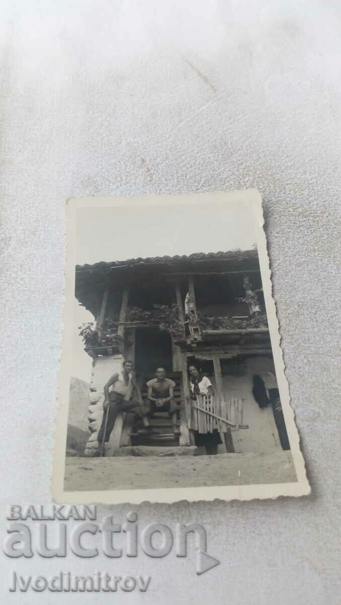 Foto Doi bărbați și o femeie pe scările unei case de țară