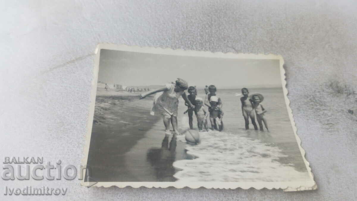 Photo A woman and six small children on the beach
