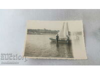 Photo Three men in front of a sailboat in the sea