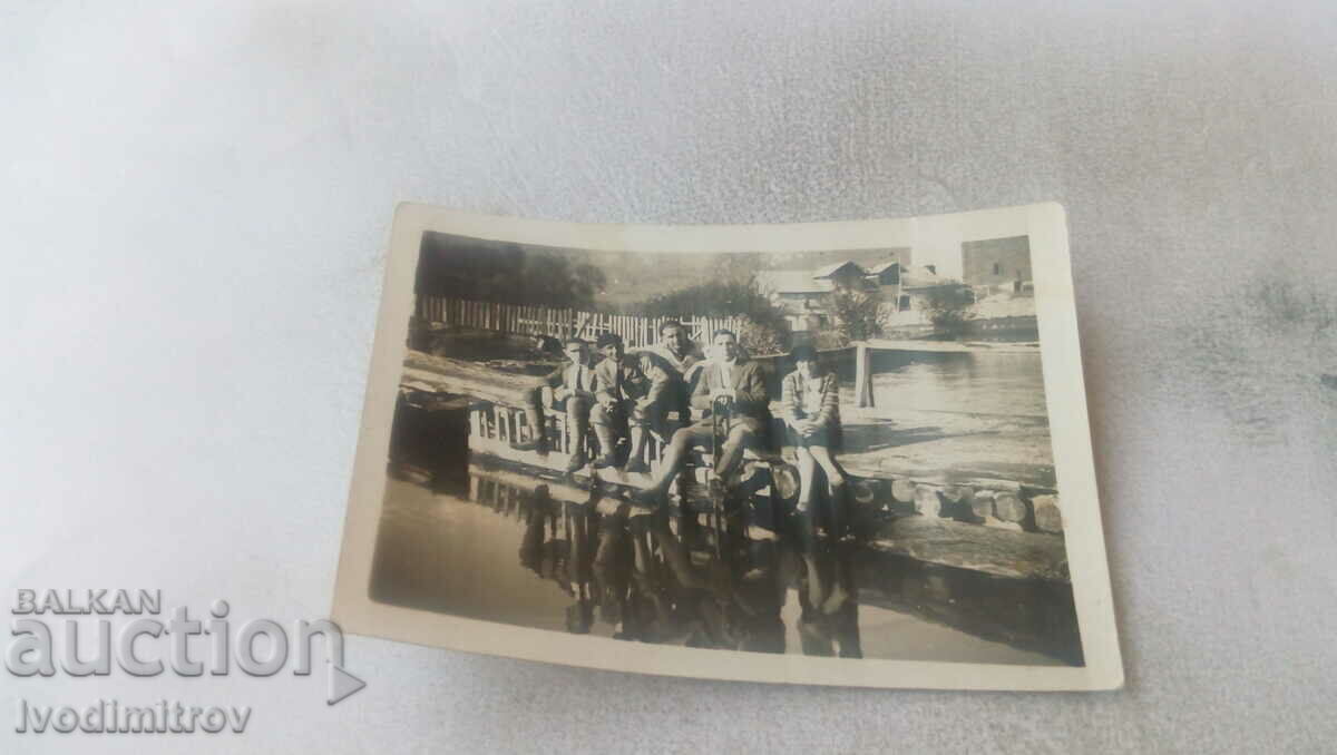Photo A woman and five men on a wooden bridge over a river
