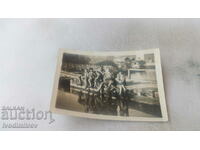 Photo A woman and five men on a wooden bridge over a river