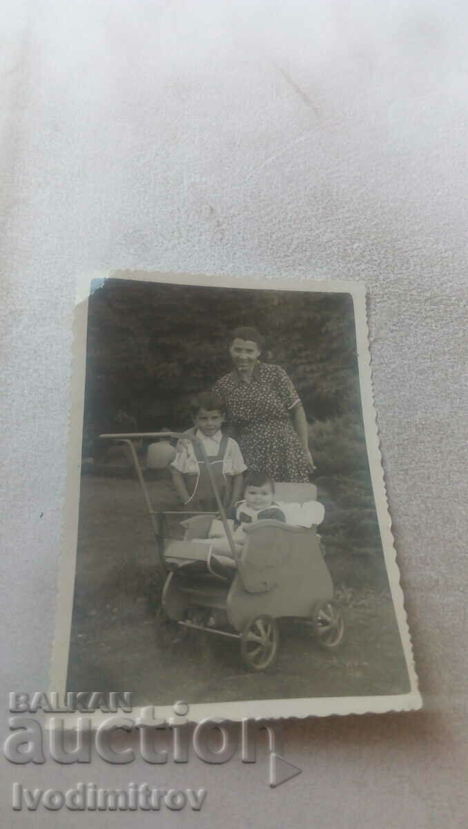 Photo Woman boy and baby girl in a retro baby carriage