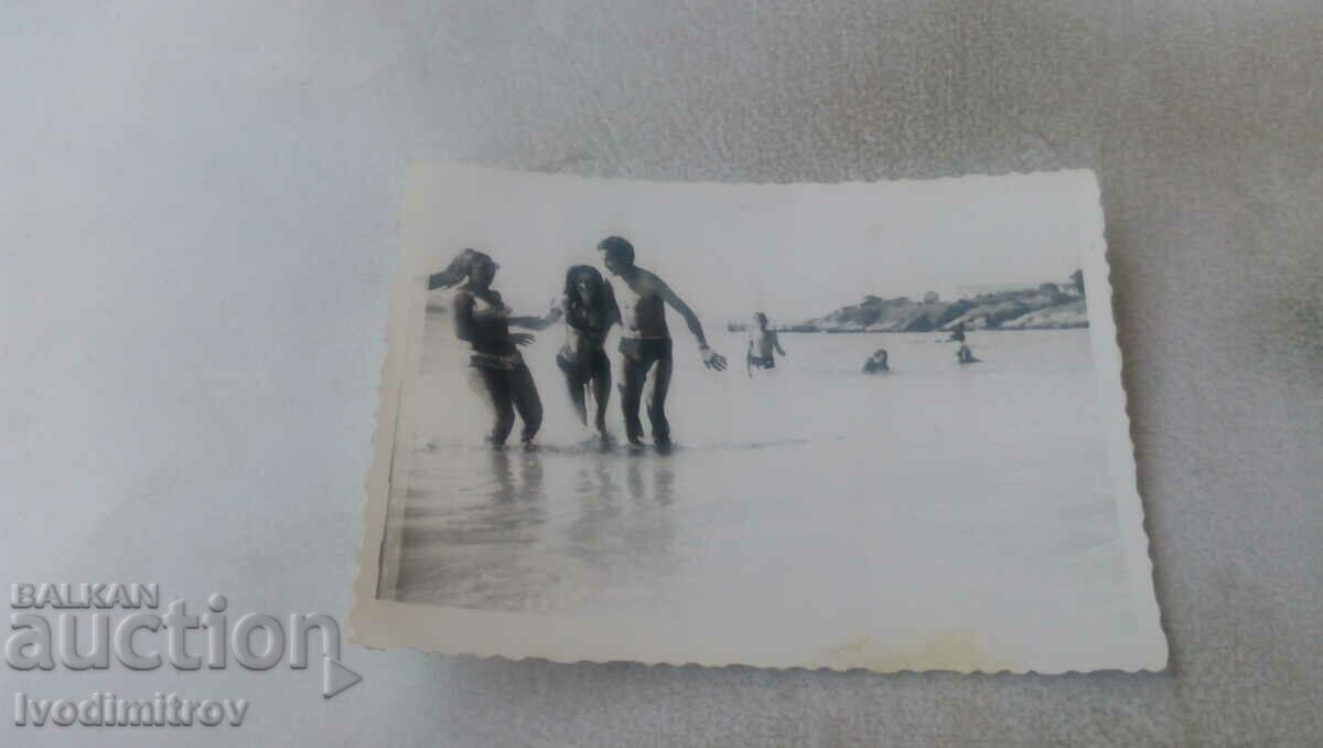 Φωτογραφία Ένας νεαρός άνδρας και δύο κορίτσια στην είσοδο της παραλίας