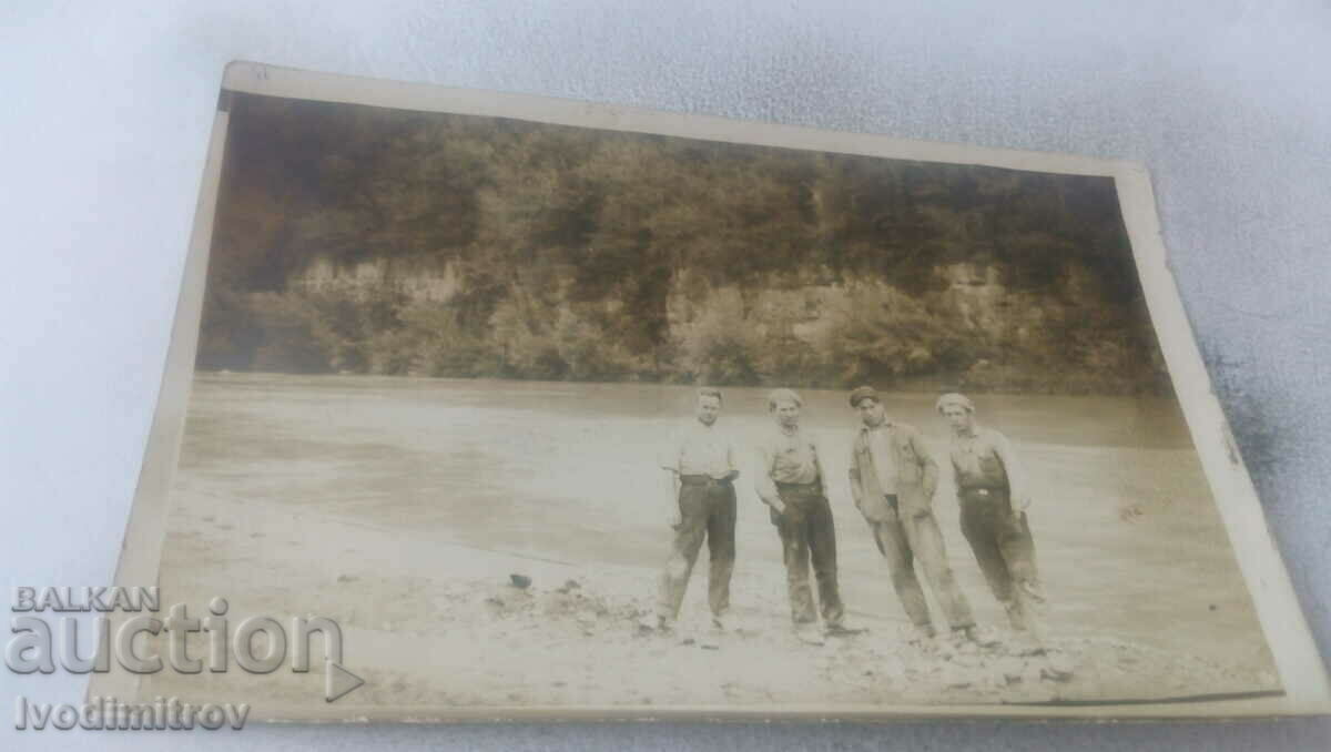 Photo Four men by a river