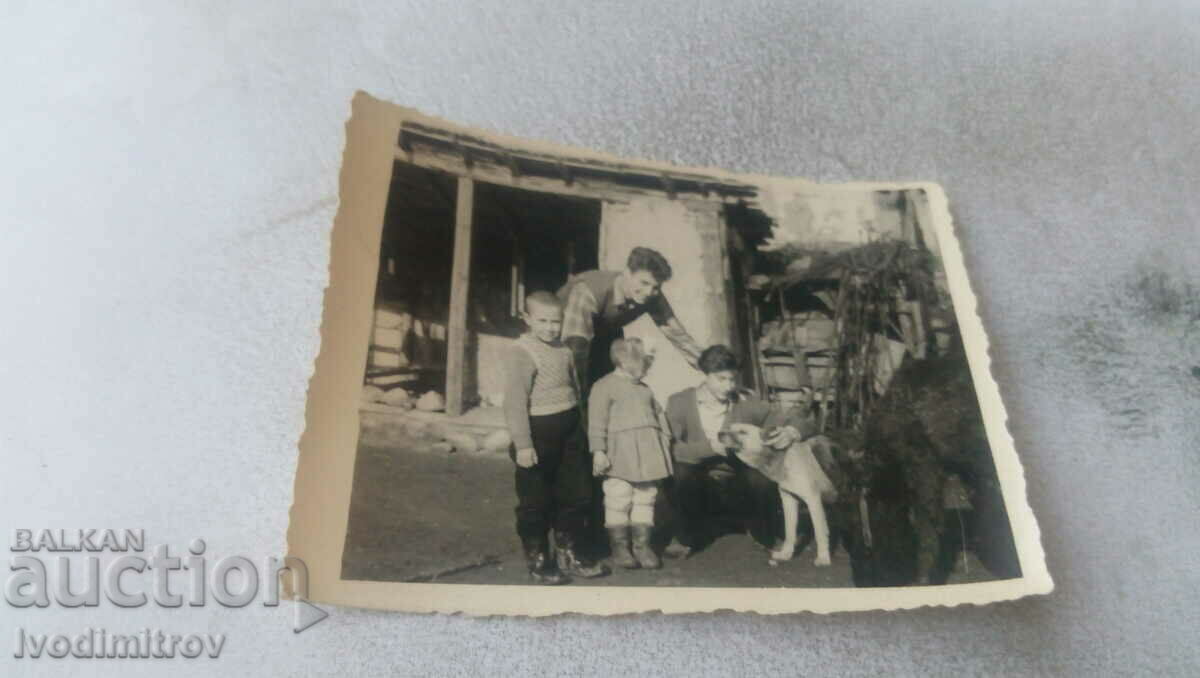 Photo Two young people, two children and a dog in the yard of a country house