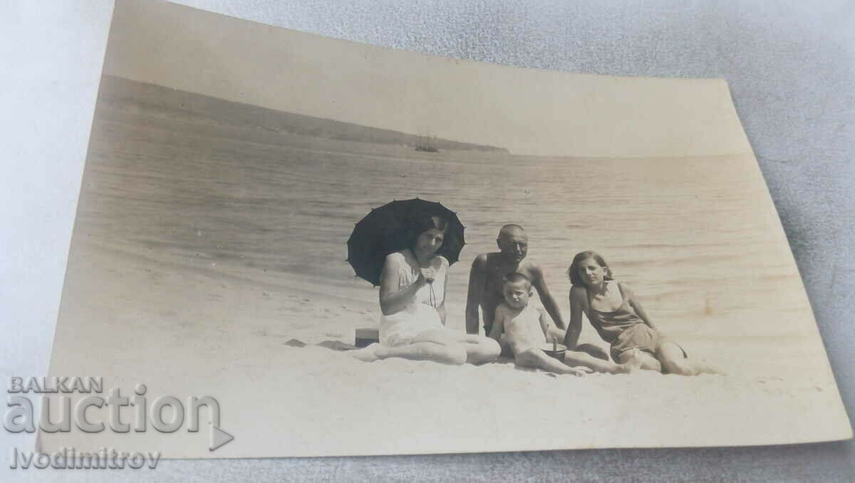 Doamna bărbat femeie cu umbrelă neagră fată și băiețel pe plajă