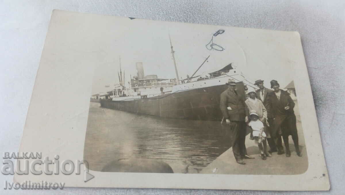 Foto Doi bărbați, două femei și o fată în fața unui vapor cu aburi pe stradă