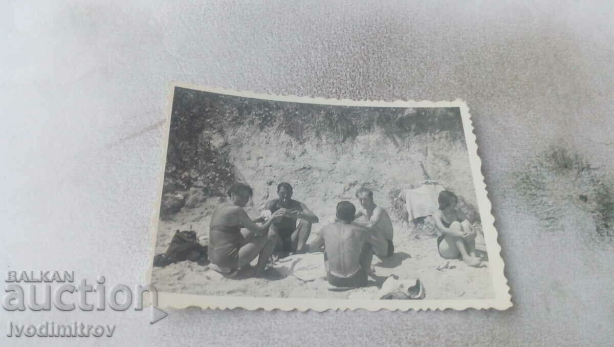 Foto Femeie și trei bărbați jucând cărți pe plajă