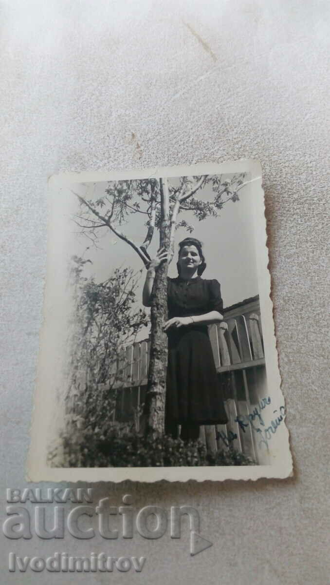 Φωτογραφία Νεαρή γυναίκα δίπλα σε ένα δέντρο στην αυλή