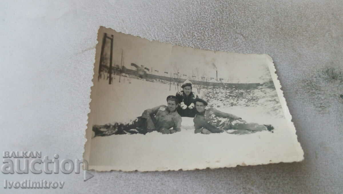 Photo Three young men lying on the snow in winter