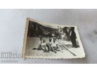 Снимка Четири млади мъже седящи на павирана улица