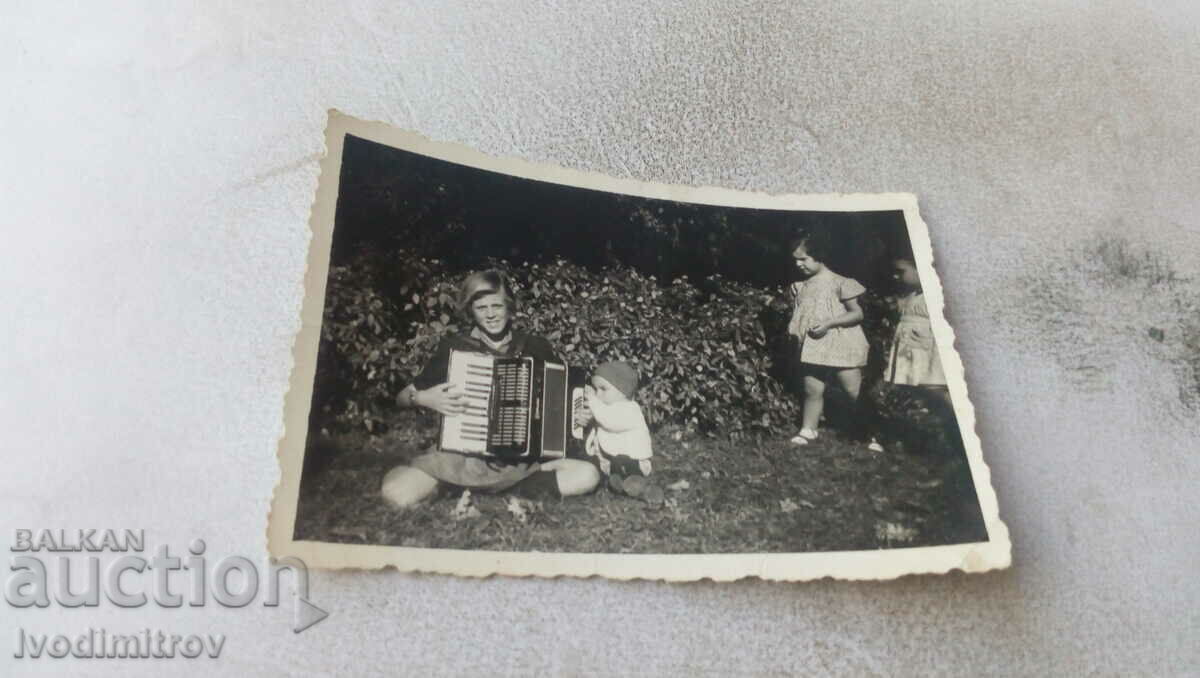 Photo A young man with an accordion and three small children