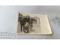 Foto Femeie și trei copii în fața caselor vechi