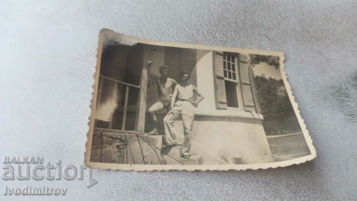 Picture A man in pants and a clothed man on the stairs of a house