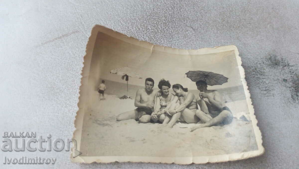 Photo Two young men and two women on the beach