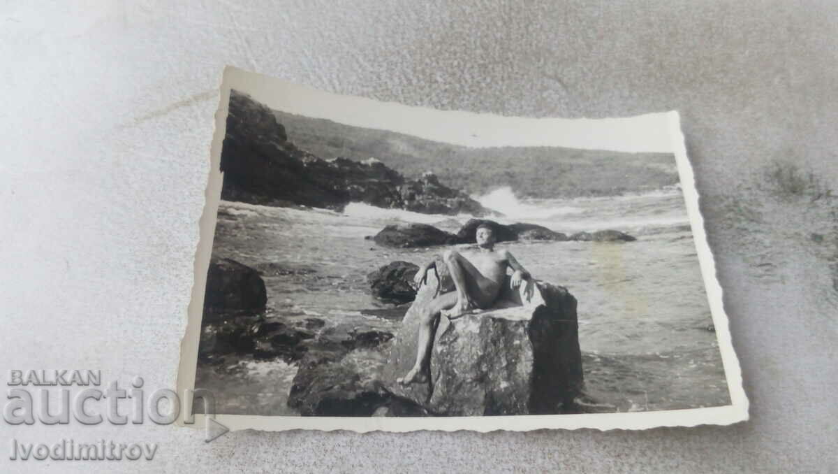 Φωτογραφία Νεαρός άνδρας σε έναν βράχο στην ακτή