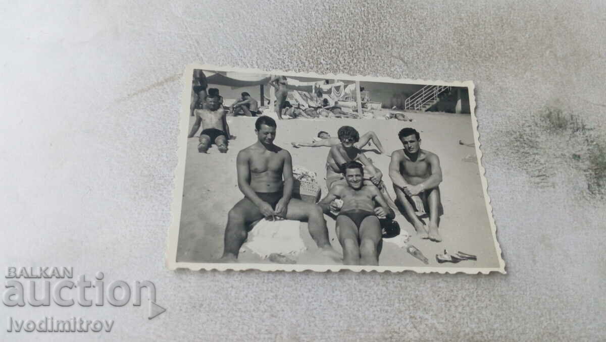 Photo Three young men and a woman on the beach