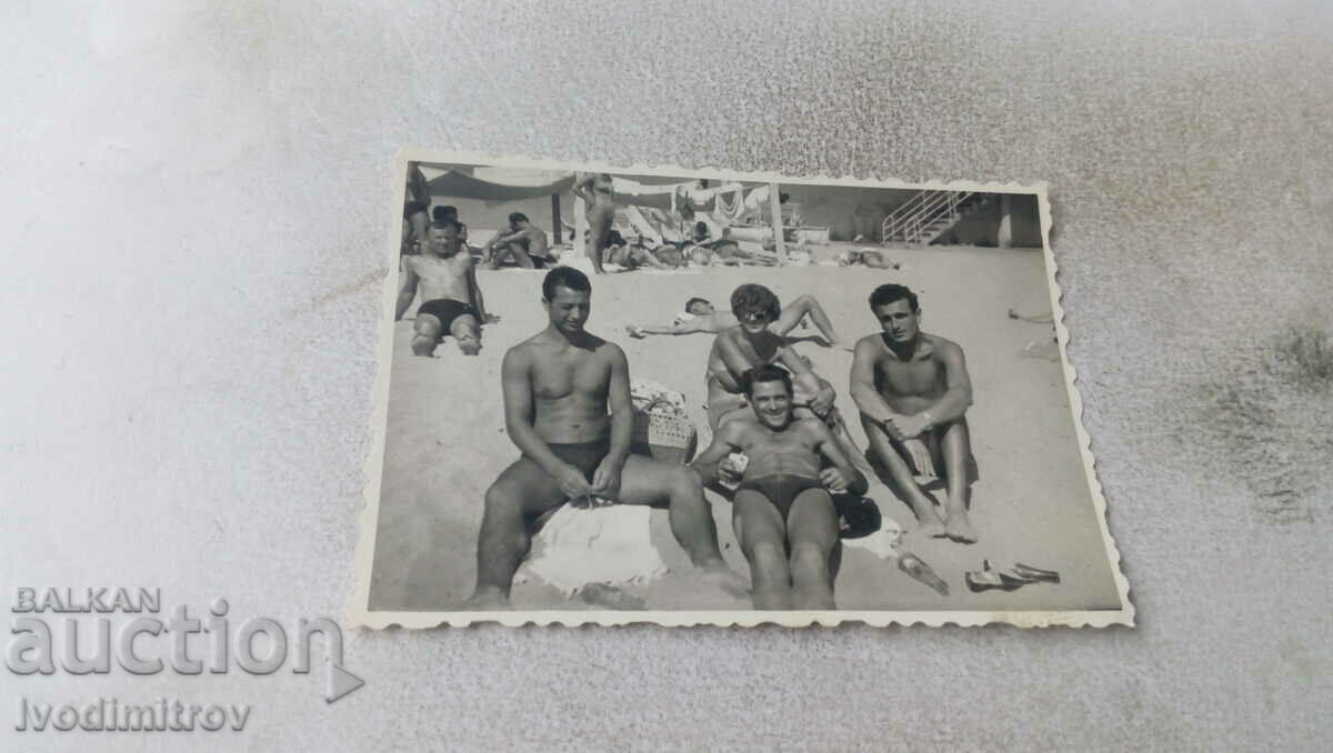 Photo Three young men and a woman on the beach