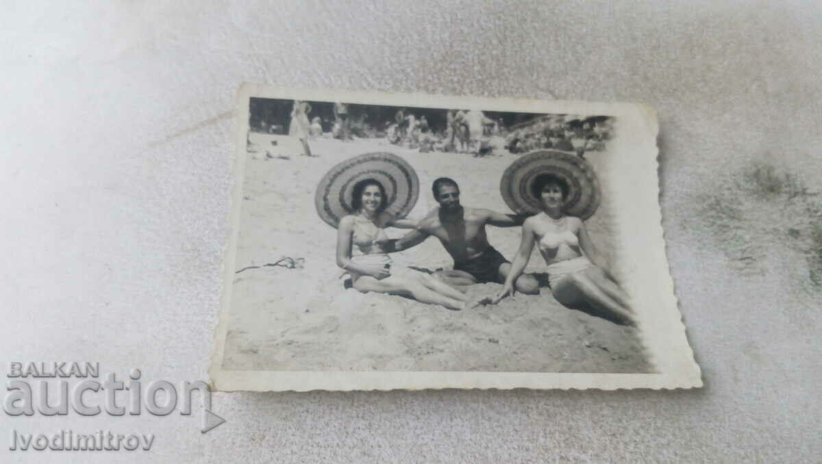 Photo A man and two young girls with sombreros on the beach