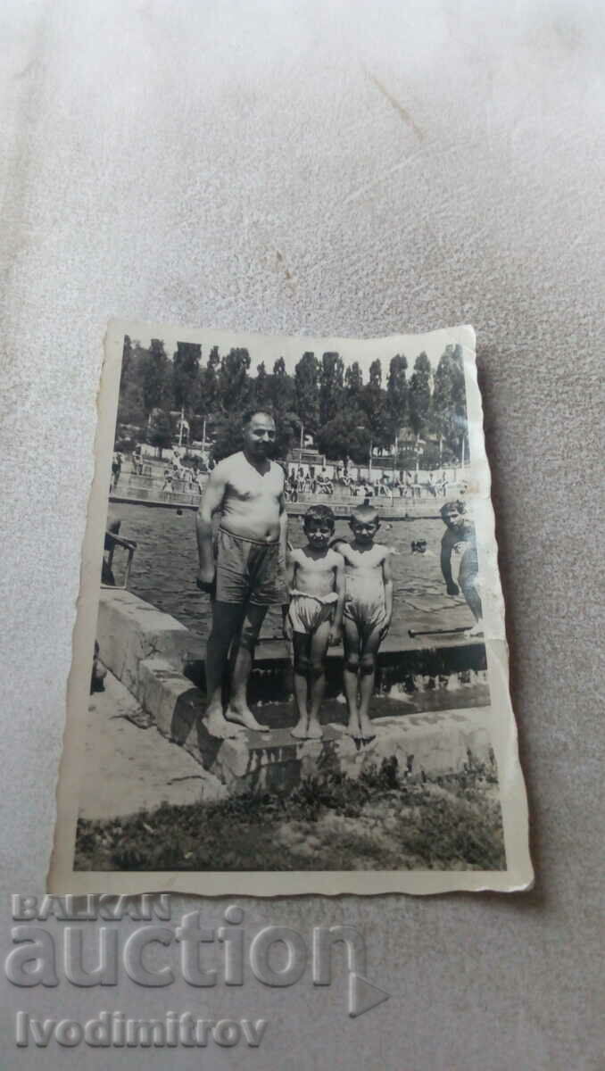 Photo A man and two little boys in retro swimwear at a pool