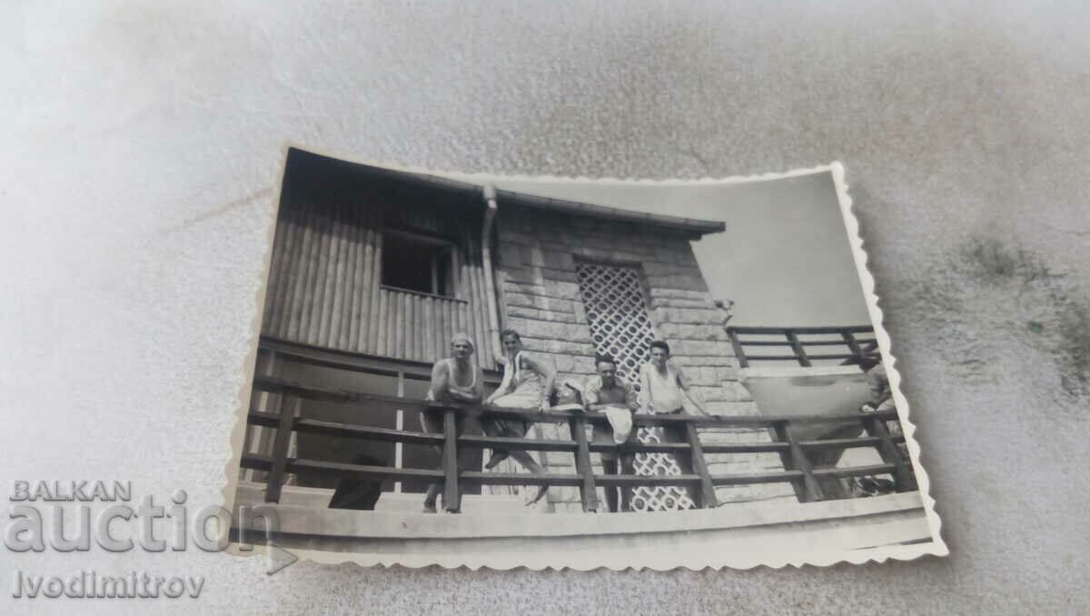 Photo Woman and three men on the railing of a hut in winter