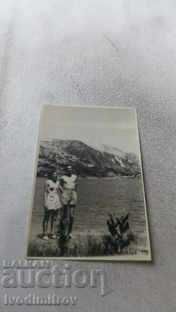 Fotografie O femeie și un bărbat în pantaloni scurți lângă un lac de munte
