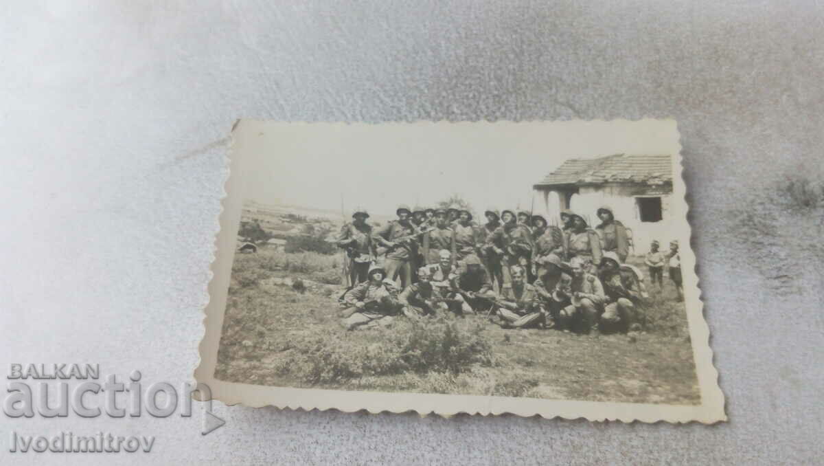 Foto Ofițer și soldați cu căști în fața unei case vechi