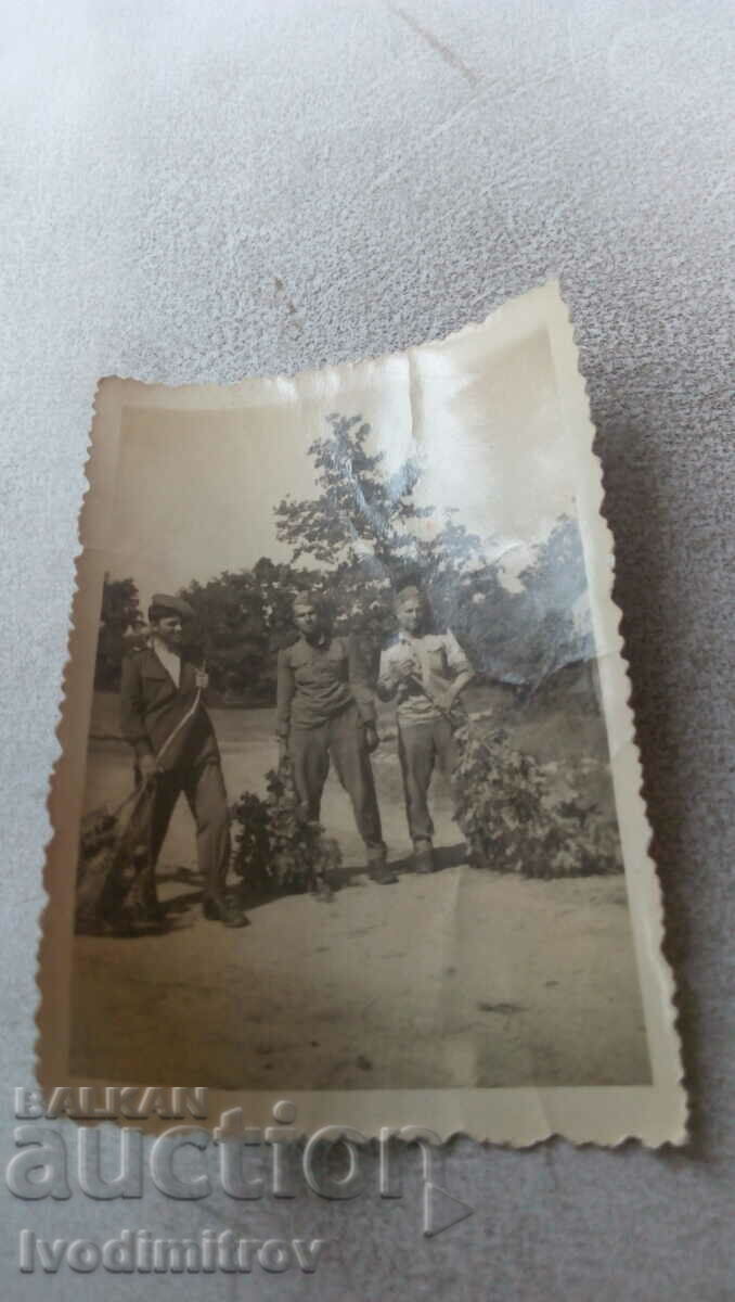Photo Three soldiers with cut branches in their hands