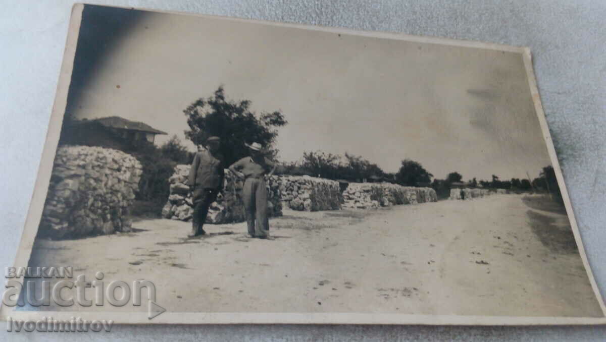 Photo Two men next to stone chambers along the road