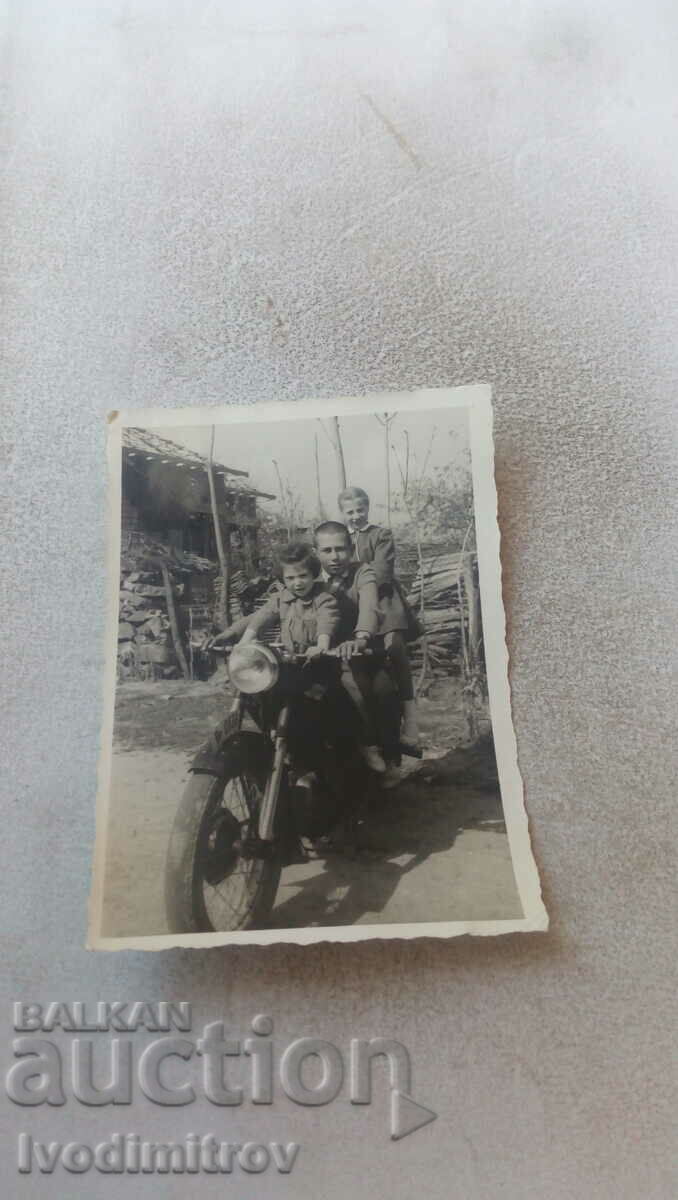 Foto Doi băieți și o fată pe o motocicletă de epocă