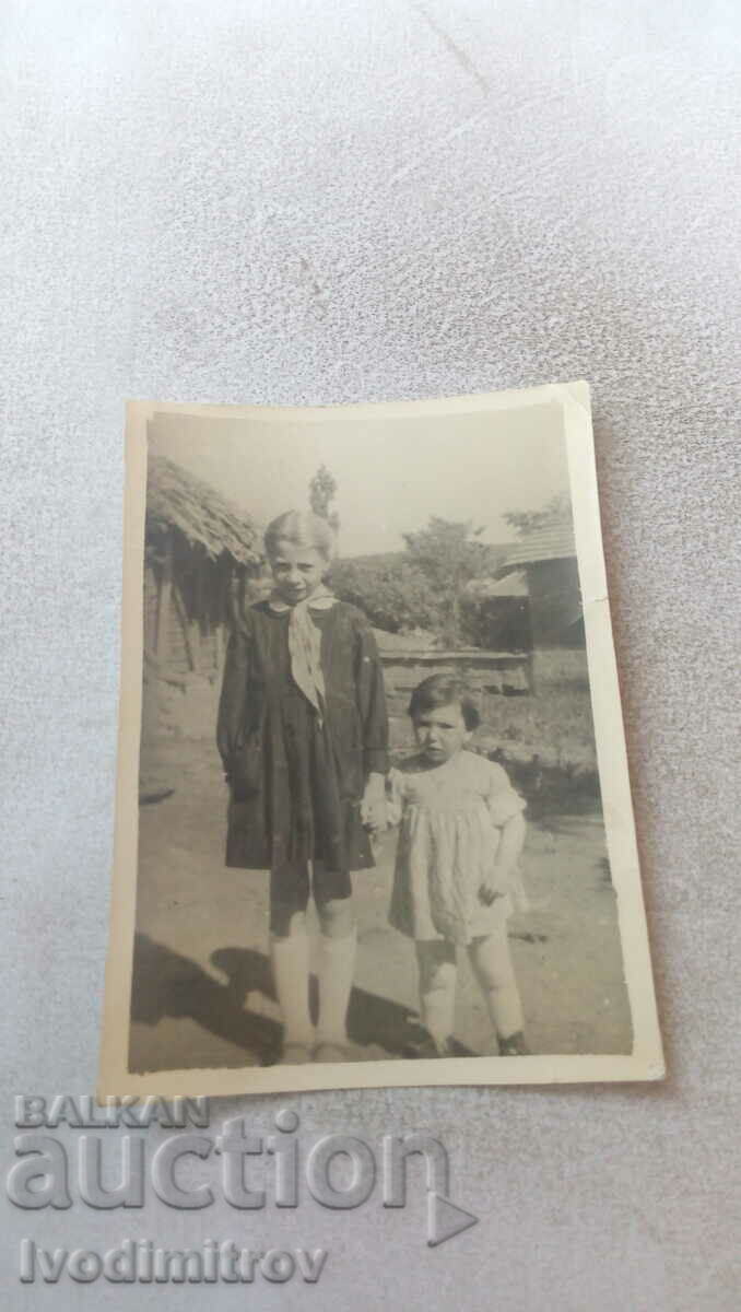 Foto Două fetițe în curtea unei case de țară