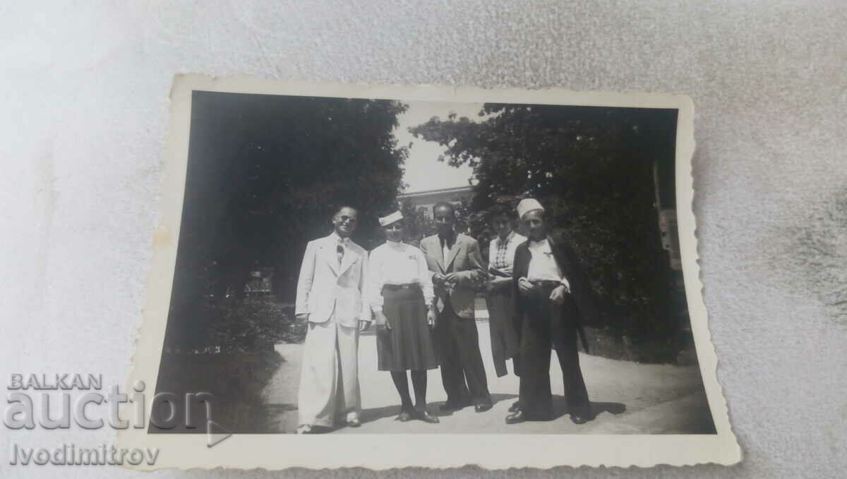 Photo Three men and two women with boyish caps on the alley