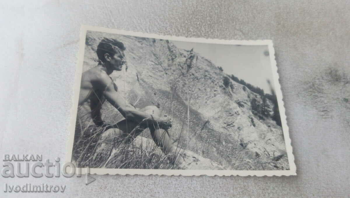 Photo Man in shorts sitting on a rock
