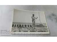 Fotografie Un bărbat în costum de baie fixează o plasă de pescuit pe o navă